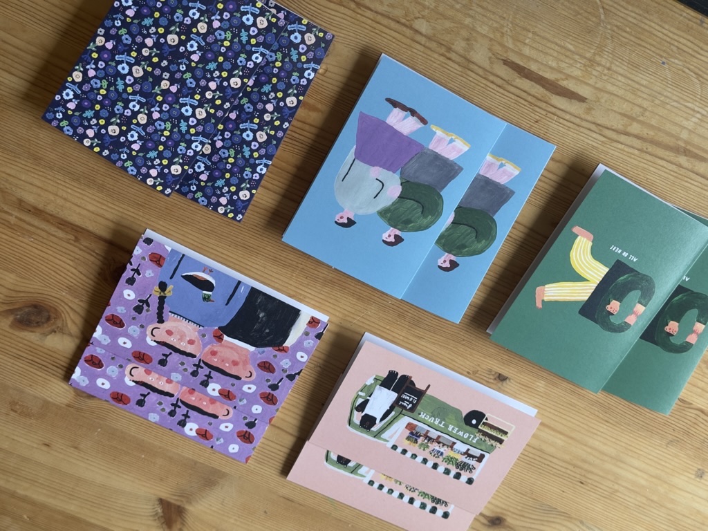 Ten illustrated Thinking of You greeting cards arranged on a wooden table.