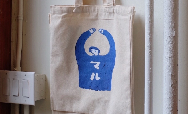 A cream Babincho tote bag hanging in front of a curtain